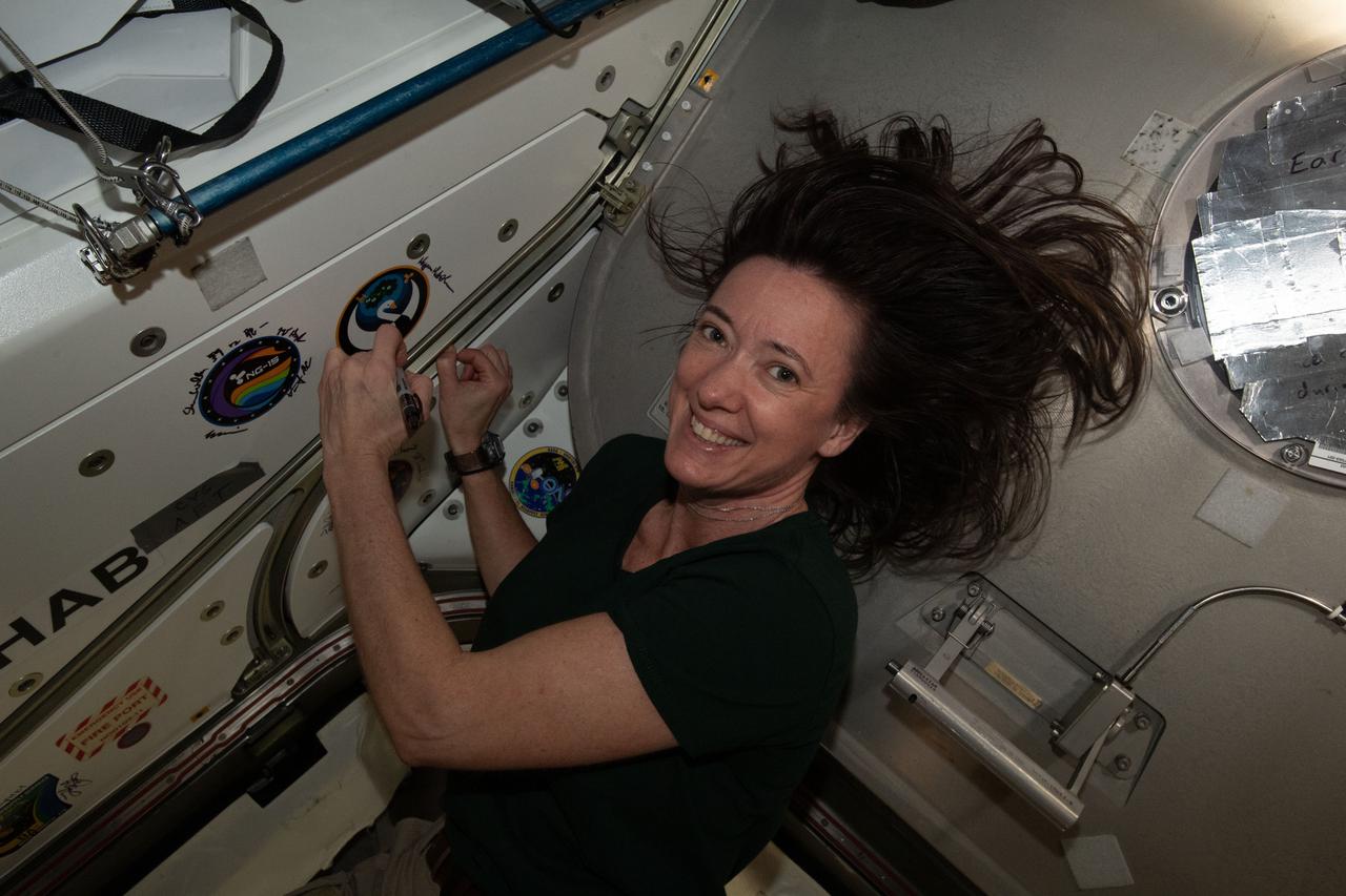 iss065e389491 (Sept. 17, 2021) --- NASA astronaut and Expedition 65 Flight Engineer Megan McArthur signs her name around the Northrop Grumman-16 (NG-16) mission insignia sticker affixed to the vestibule in between the Unity module and the Cygnus space freighter.