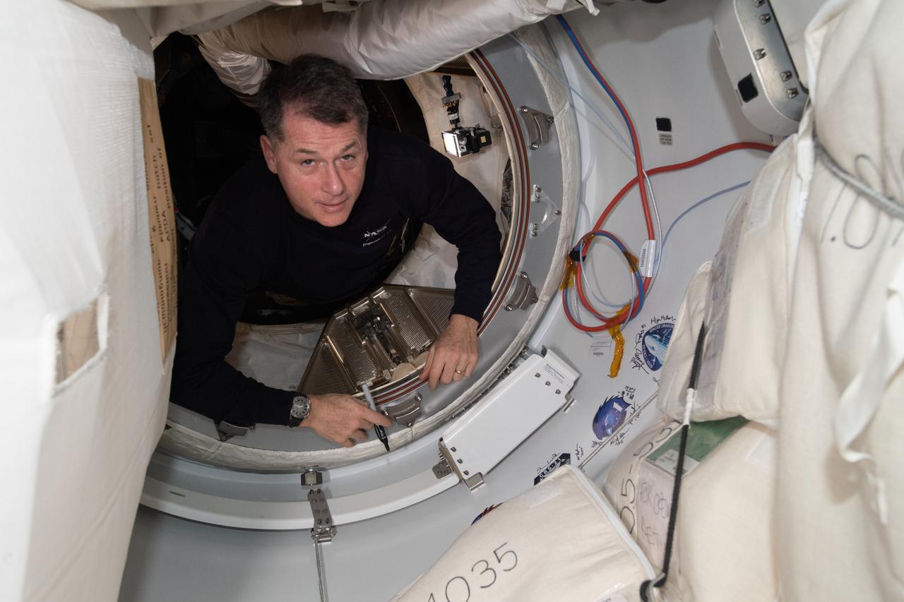 iss065e389568 (Sept. 17, 2021) --- NASA astronaut and Expedition 65 Flight Engineer Shane Kimbrough signs his name around the SpaceX Crew-2 mission insignia sticker affixed to the vestibule in between the Harmony module and its space-facing international docking adapter where the SpaceX Crew Dragon Endeavour is docked.