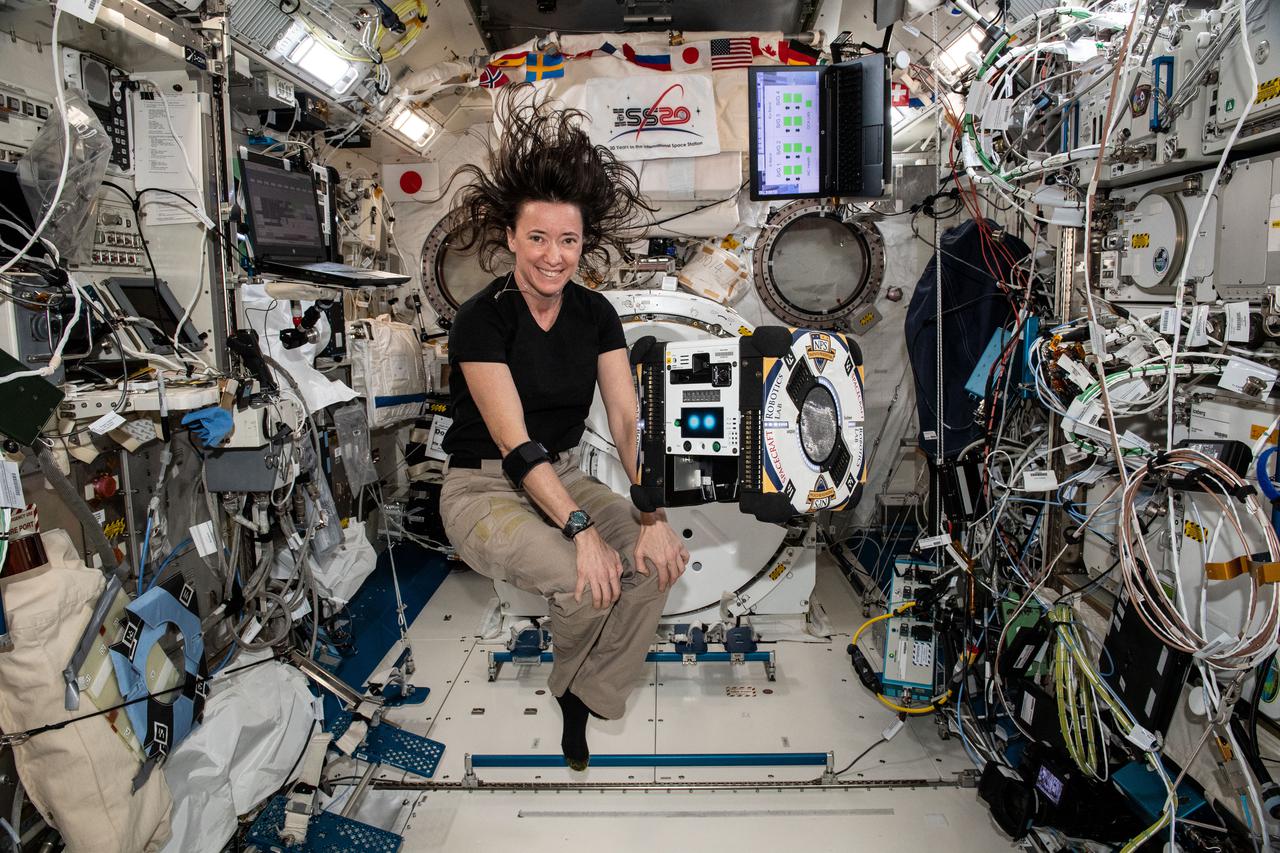 iss065e444043 (Oct. 8, 2021) --- NASA astronaut and Expedition 65 Flight Engineer Megan McArthur poses with an AstroBee robotic free-flying assistant inside the International Space Station's Kibo laboratory module.