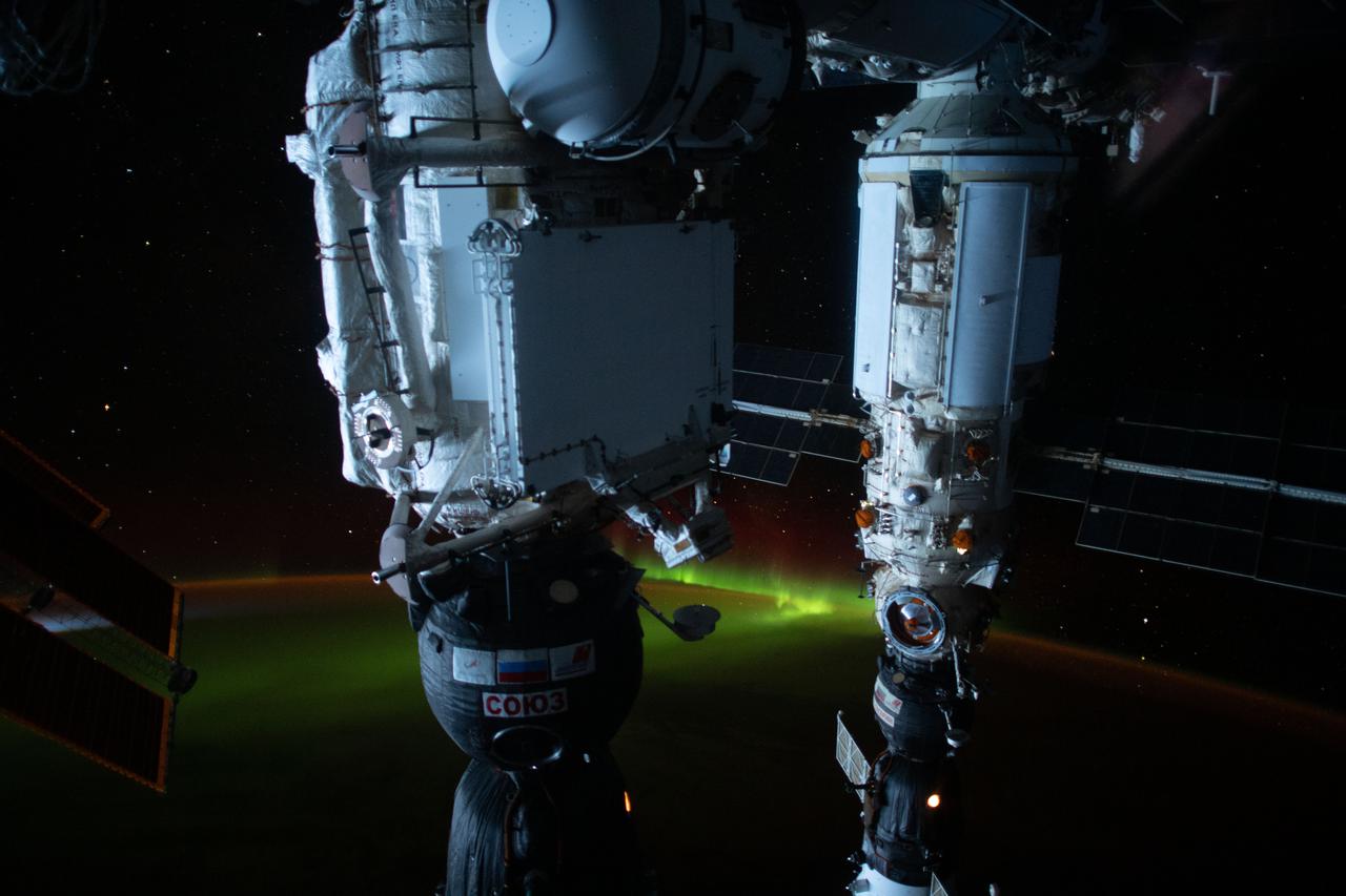 iss065e455153 (Oct. 9, 2021) --- An aurora is pictured below the International Space Station as it was orbiting 274 miles above the southern Pacific Ocean just south of Auckland Island, New Zealand. In the foreground (from left) are, the Soyuz MS-19 crew ship docked to the Rassvet module and the Soyuz MS-18 crew ship docked to the Nauka multipurpose laboratory module.