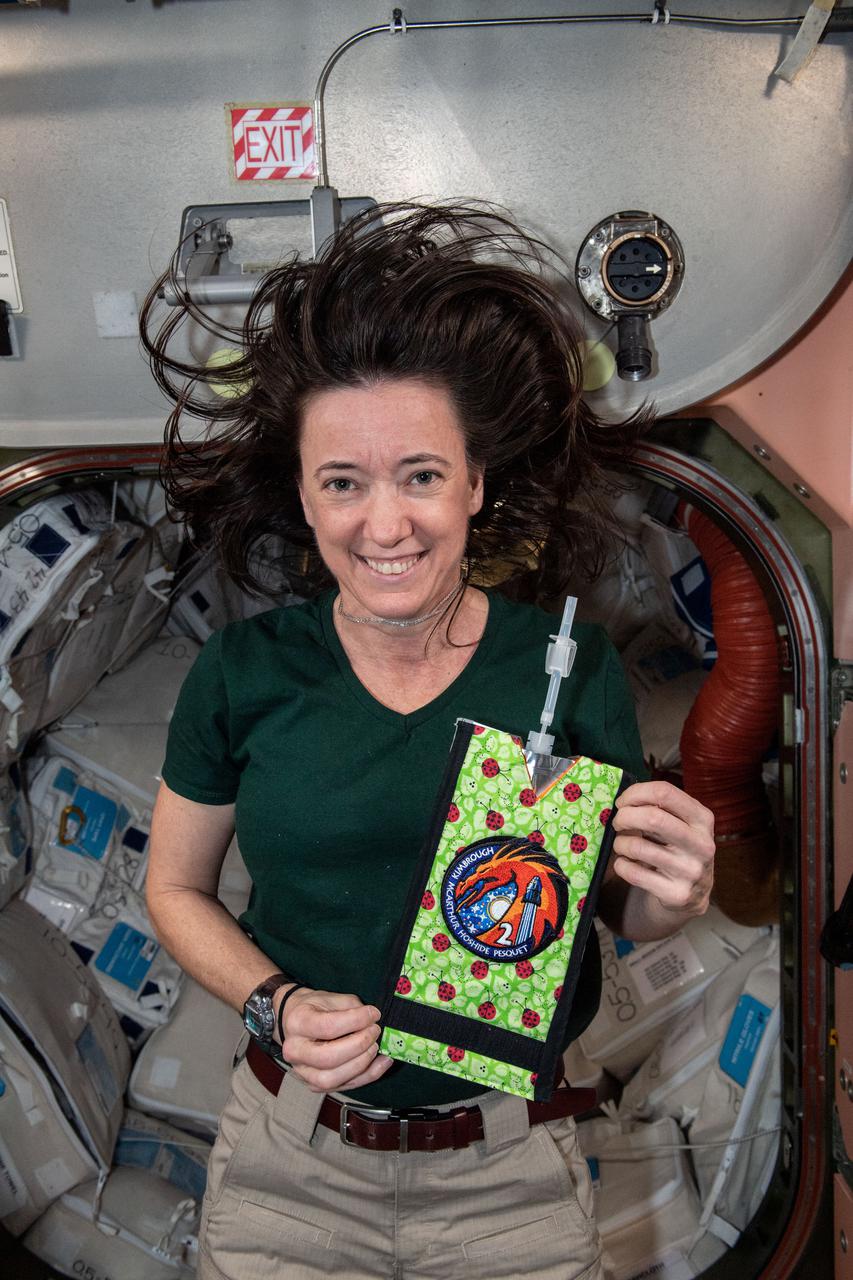 iss066e008128 (Oct. 21, 2021) --- NASA astronaut and Expedition 66 Flight Engineer Megan McArthur holds a personalized drink pouch bearing the SpaceX Crew-2 mission insignia patch.