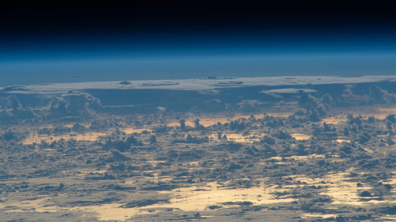 iss066e037531 (Nov. 4, 2021) --- Clouds protrude above the north Atlantic Ocean, with the Sun's glint beaming off the golden-hued waters, in this oblique photograph from the International Space Station as it orbited 262 miles above just off the coast of Nova Scotia, Canada.