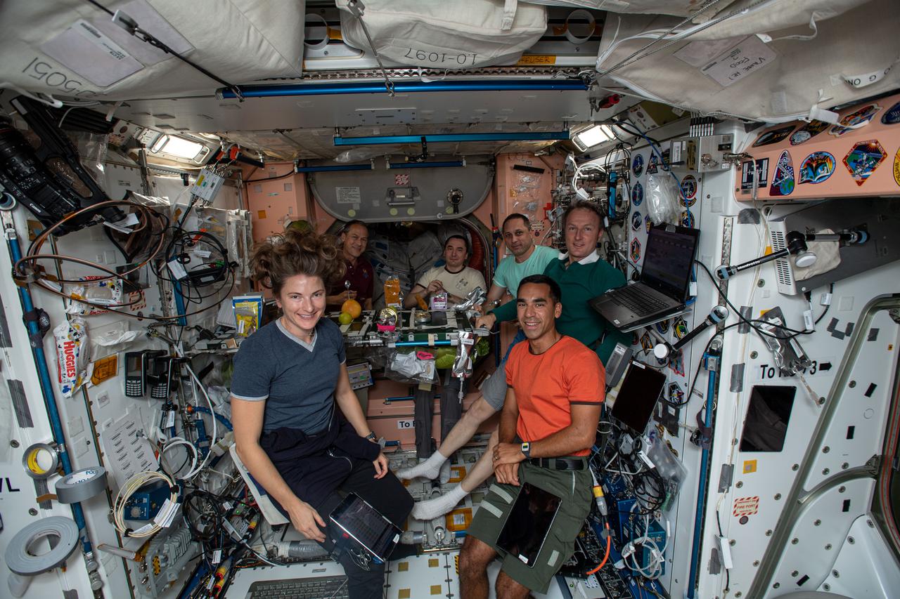 iss066e083000 (Nov. 25, 2021) --- Expedition 66 crew members gather for a Thanksgiving meal inside the International Space Station's Unity module. Clockwise from left, are NASA astronauts Kayla Barron and Thomas Marshburn; Roscosmos cosmonauts Pyotr Dubrov and Anton Shkaplerov; ESA (European Space Agency) astronaut Matthias Maurer; and NASA astronaut Raja Chari. Not pictured is NASA astronaut Mark Vande Hei who was photographing his crewmates.