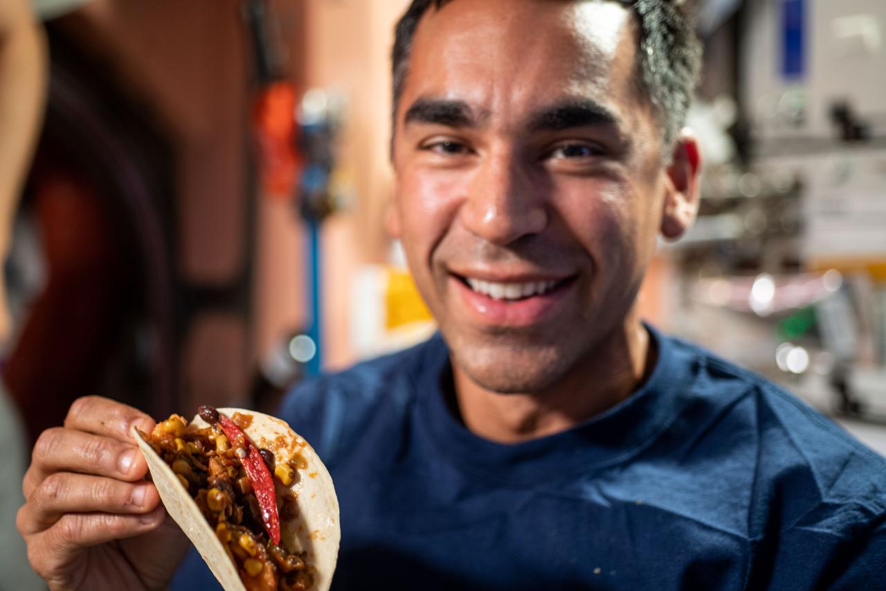 iss066e083715 (Nov. 26, 2021) --- NASA astronaut and Expedition 66 Flight Engineer Raja Chari is ready for taco night as he shows off a taco made with fresh chile peppers harvested from inside the International Space Station's Advanced Plant Habitat.