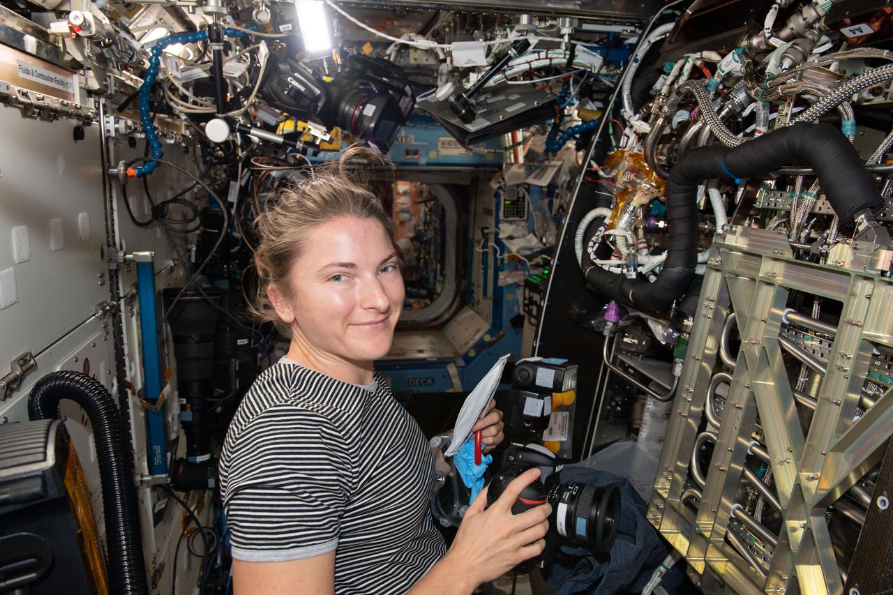 iss066e086562 (Dec. 4, 2021) --- NASA astronaut and Expedition 66 Flight Engineer Kayla Barron is pictured inspecting and photographing components inside the Materials Science Research Rack that enables the observation of chemical and thermal properties of materials free from the effects of gravity.