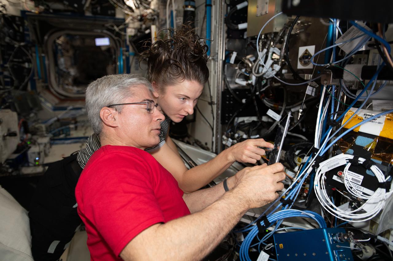 iss066e088377 (Dec. 9, 2021) --- NASA astronauts Mark Vande Hei and Kayla Barron set up the Fluids Integrated Rack for a space physics study that may improve thermal systems for Earth and other planetary environments.