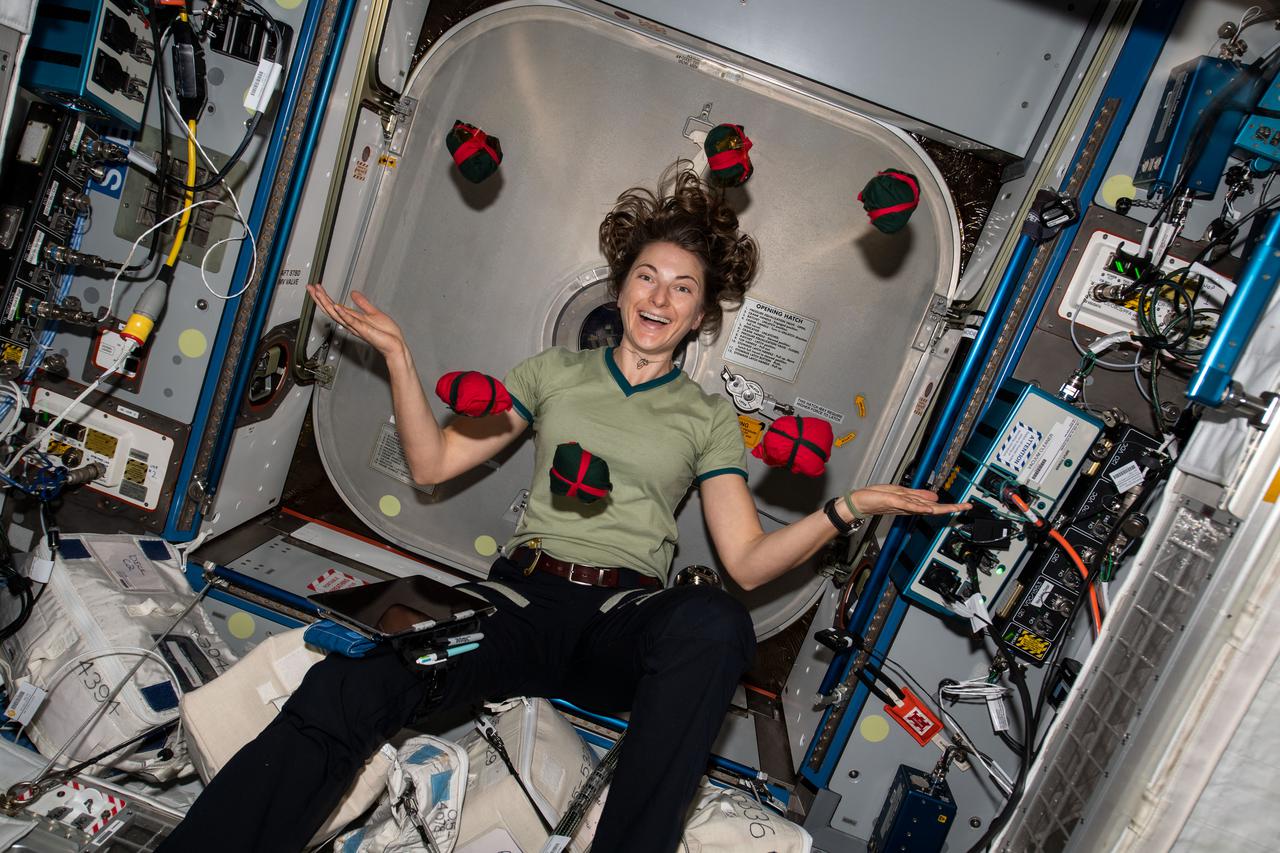 iss066e093622 (Dec. 20, 2021) --- NASA astronaut and Expedition 66 Flight Engineer Kayla Barron is pictured seemingly juggles Christmas presents aboard the International Space Station.