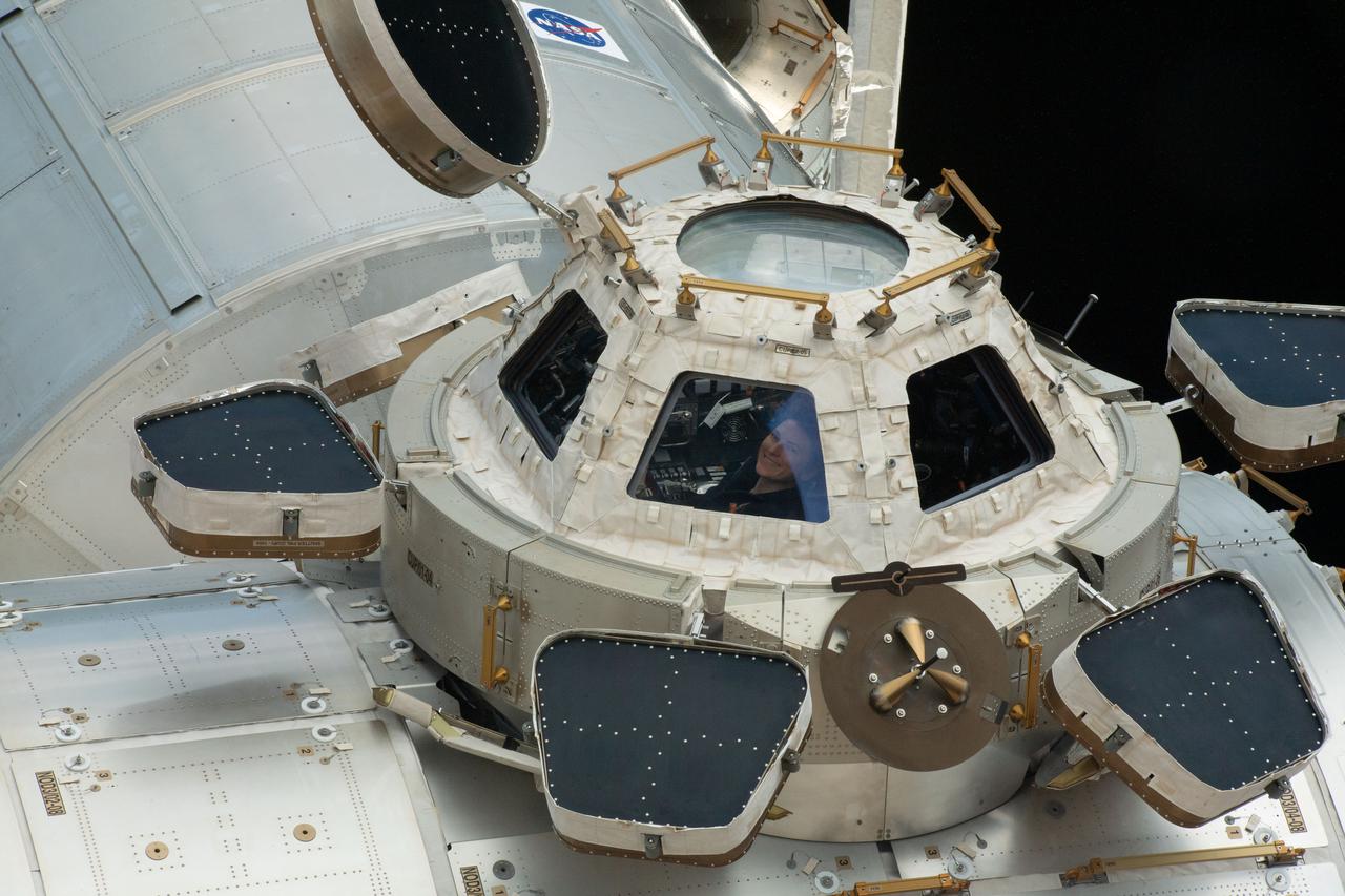 iss066e113975 (Jan. 16, 2022) --- NASA astronaut and Expedition 66 Flight Engineer Kayla Barron smiles while peering out from a window inside the cupola, the International Space Station's "window to the world."