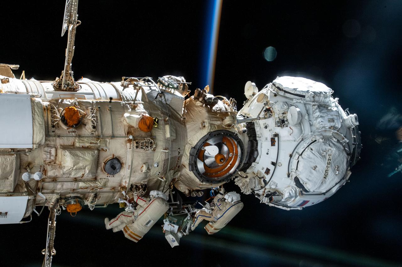 iss066e119043 (Jan. 19, 2022) --- Roscosmos cosmonauts (from bottom left) Anton Shkaplerov and Pyotr Dubrov work outside the Nauka multipurpose laboratory module during a spacewalk that lasted seven hours and 11 minutes. Attached to Nauka at right, is the Prichal docking module that was configured and activated during the spacewalk.