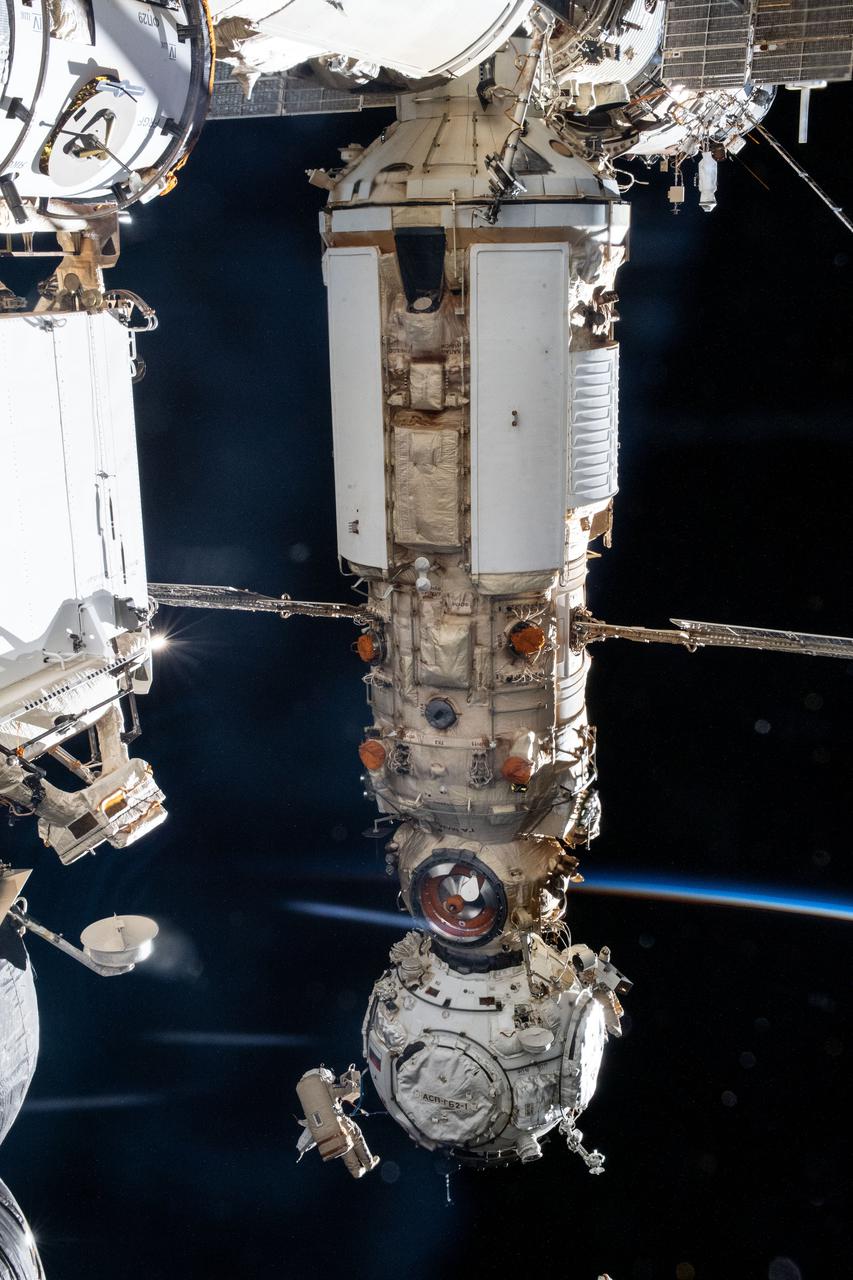 iss066e121432 (Jan. 19, 2022) --- The Prichal docking and the Nauka multipurpose laboratory module figure prominently in this image taken during a spacewalk with cosmonauts Anton Shkaplerov (at bottom) and Pyotr Dubrov (partially obscured behind Prichal) who outfitted both modules to integrate with the International Space Station.