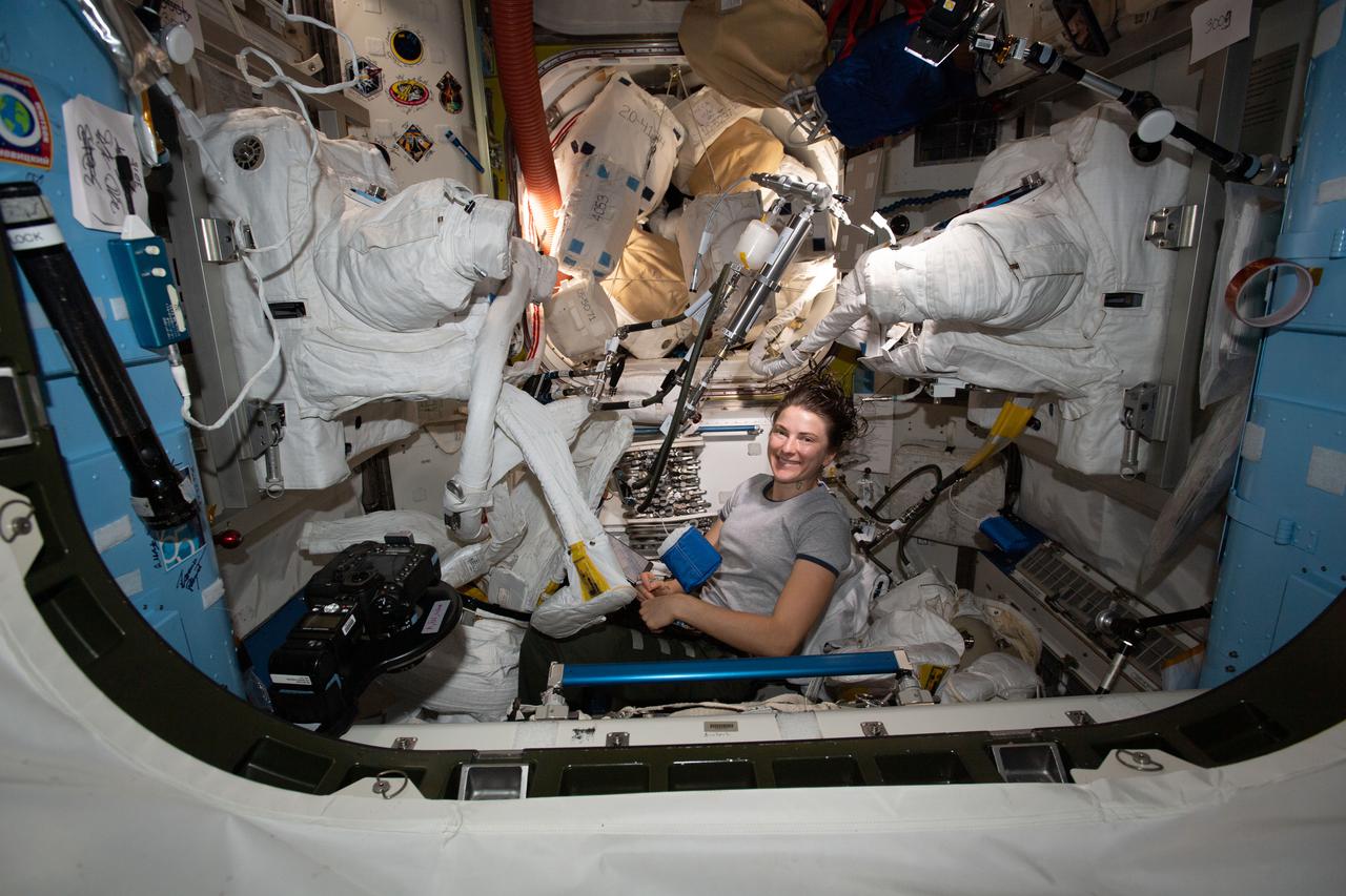 iss066e130323 (Jan. 28, 2022) --- NASA astronaut and Expedition 66 Flight Engineer Kayla Barron cleans cooling loops and water lines inside a pair of U.S. spacesuits aboard the International Space Station's Quest airlock.
