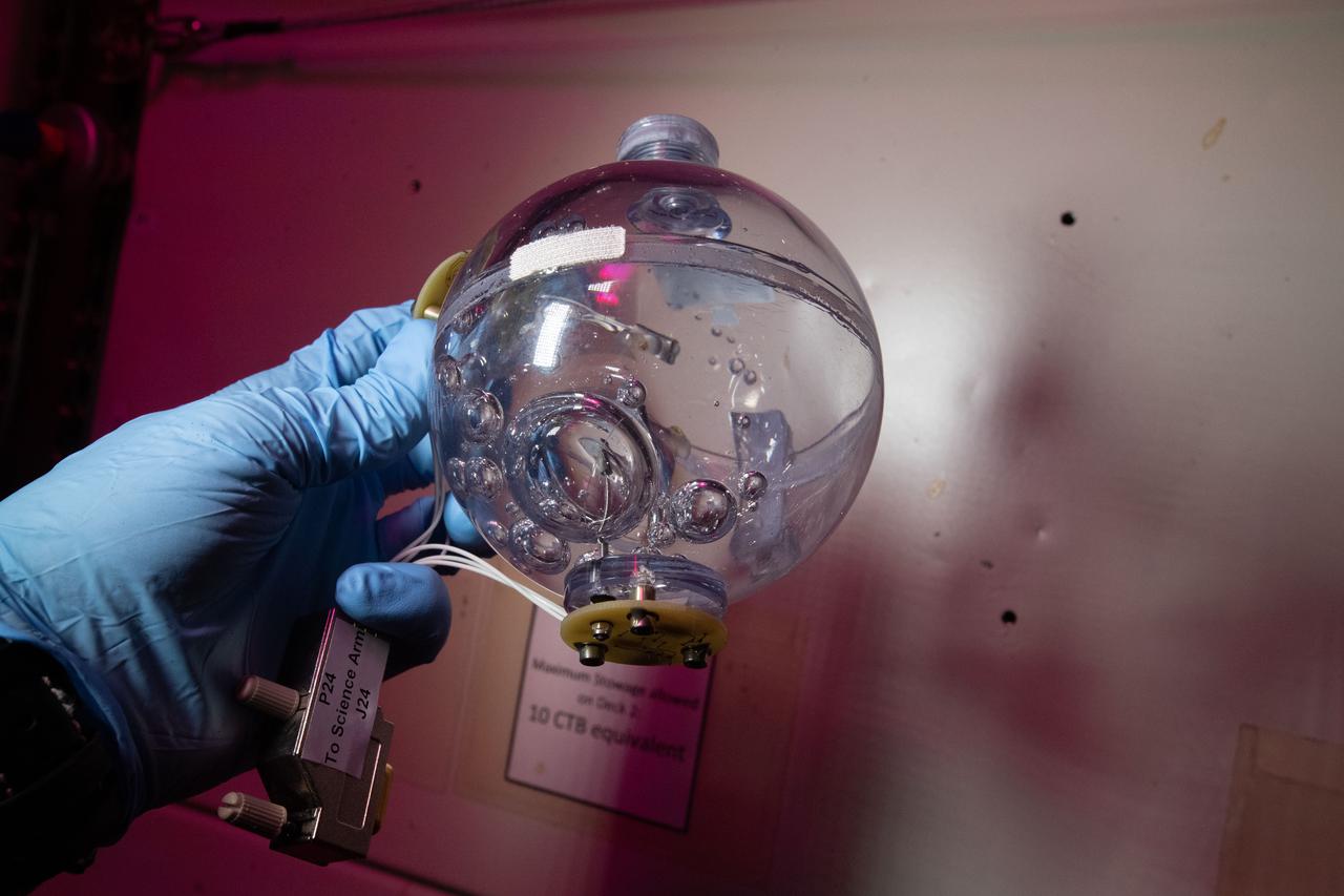 iss066e146884 (2/22/2022) --- A view of a transparent FLUIDICS sphere aboard the International Space Station (ISS).  The FLUIDICS investigation evaluates the Center of Mass (CoM) position regarding a temperature gradient on a representation of a fuel tank. The observation of capillary wave turbulence on the surface of a fluid layer in a low-gravity environment can provide insights into measuring the existing volume in a sphere.
