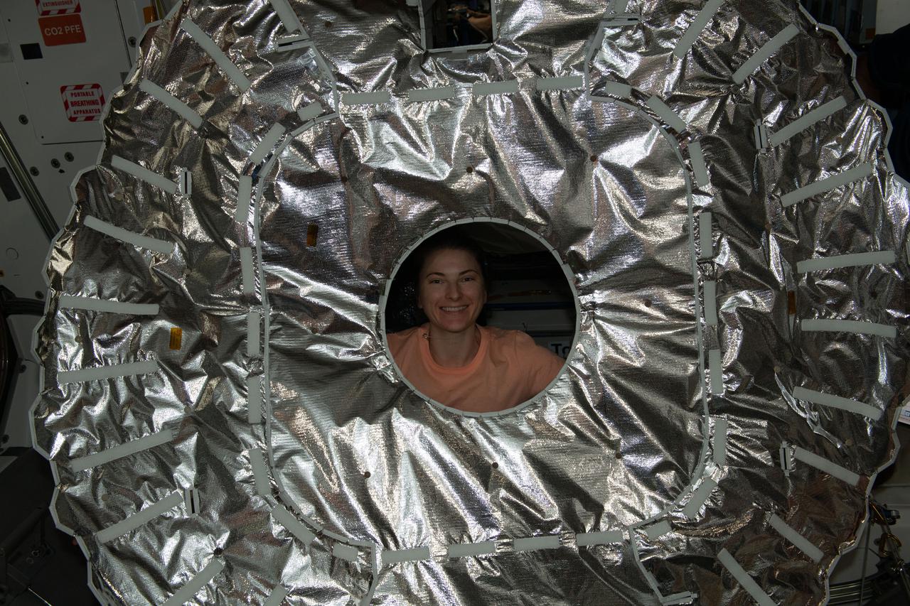 iss066e147566 (Feb. 21, 2022) --- NASA astronaut and Expedition 66 Flight Engineer Kayla Barron is pictured after removing a thermal blanket that covered the hatch to the Cygnus space freighter. The U.S. resupply ship had been captured and installed wth the Canadarm2 robotic arm to the International Space Station's Unity module a few hours ealrier.