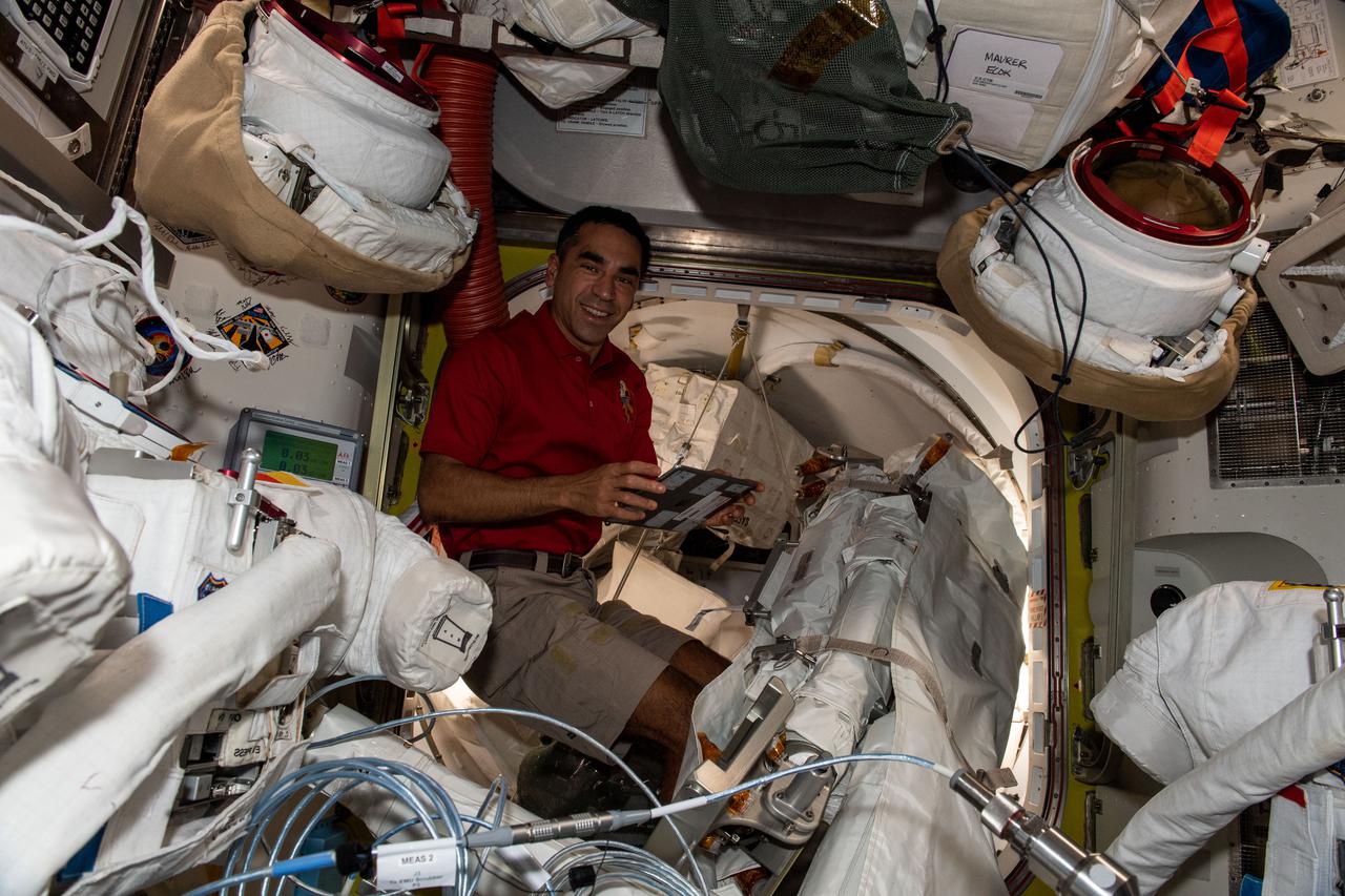 iss066e155773 (March 1, 2022) --- NASA astronaut and Expedition 66 Flight Engineer Raja Chari scrubs U.S. spacesuit cooling loops inside the Interational Space Station's Quest airlock.