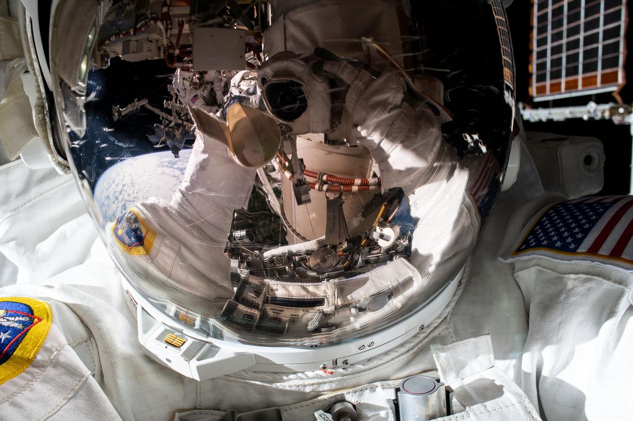 iss066e166325 (March 15, 2022) --- NASA astronaut Kayla Barron points the camera toward herself with her spaceuit's helmet shield down and takes a "space-selfie" during a six-hour and 54-minute spacewalk to set up the orbital lab for its next roll-out solar array.