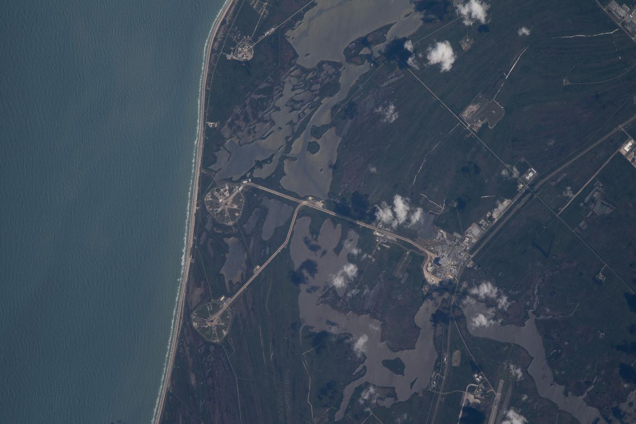 iss067e000331 (March 30, 2022) --- The International Space Station was orbiting just off the coast of Cape Canaveral, Florida, about 260 miles above the Atlantic Ocean when Expedition 67 Flight Engineer Raja Chari photographed NASA's Kennedy Space Center. The agency's two launch pads, 39A (at top) and 39B (at bottom), are clearly seen on the beach. Standing at launch pad 39B is NASA's Space Launch System (SLS) rocket with the Orion spacecraft atop. The rocket is being prepared for the uncrewed Artemis I mission "that will demonstrate NASA’s commitment and capacity to extend humanity’s presence on the Moon – and beyond."
