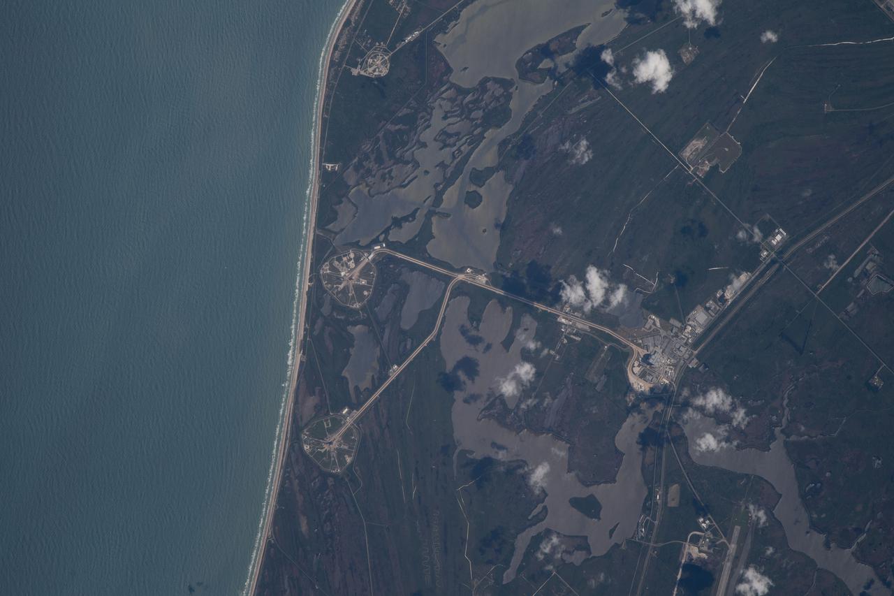 iss067e000332 (March 30, 2022) --- The International Space Station was orbiting just off the coast of Cape Canaveral, Florida, about 260 miles above the Atlantic Ocean when Expedition 67 Flight Engineer Raja Chari photographed NASA's Kennedy Space Center. The agency's two launch pads, 39A (at top) and 39B (at bottom), are clearly seen on the beach. Standing at launch pad 39B is NASA's Space Launch System (SLS) rocket with the Orion spacecraft atop. The rocket is being prepared for the uncrewed Artemis I mission "that will demonstrate NASA’s commitment and capacity to extend humanity’s presence on the Moon – and beyond."