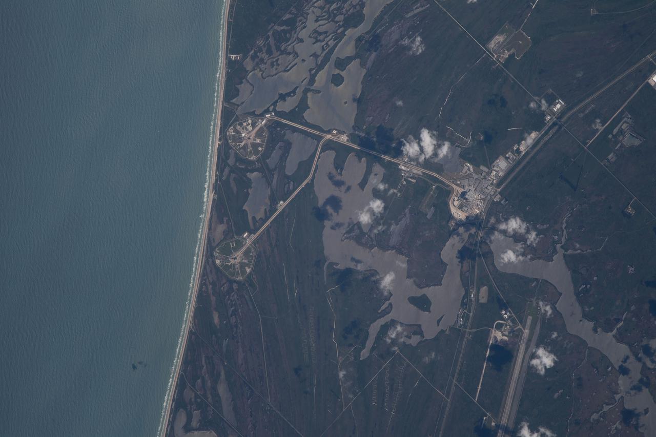 iss067e000334 (March 30, 2022) --- The International Space Station was orbiting just off the coast of Cape Canaveral, Florida, about 260 miles above the Atlantic Ocean when Expedition 67 Flight Engineer Raja Chari photographed NASA's Kennedy Space Center. The agency's two launch pads, 39A (at top) and 39B (at bottom), are clearly seen on the beach. Standing at launch pad 39B is NASA's Space Launch System (SLS) rocket with the Orion spacecraft atop. The rocket is being prepared for the uncrewed Artemis I mission "that will demonstrate NASA’s commitment and capacity to extend humanity’s presence on the Moon – and beyond."