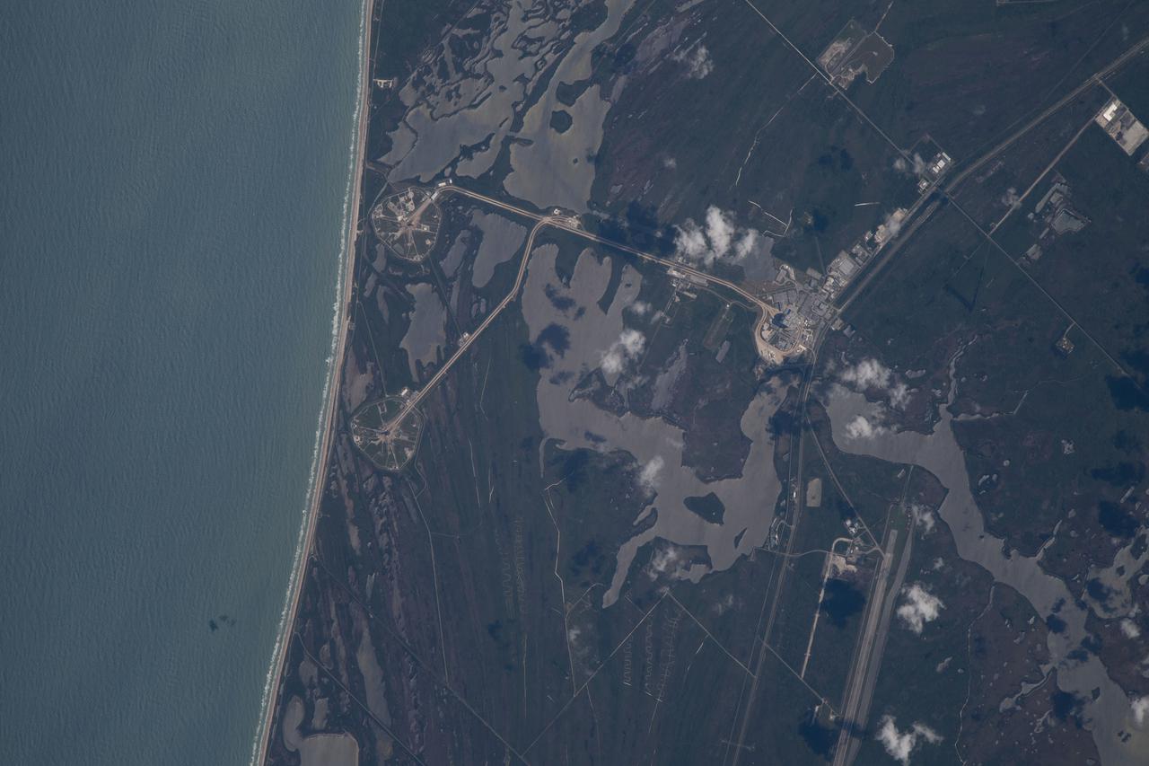 iss067e000338 (March 30, 2022) --- The International Space Station was orbiting just off the coast of Cape Canaveral, Florida, about 260 miles above the Atlantic Ocean when Expedition 67 Flight Engineer Raja Chari photographed NASA's Kennedy Space Center. The agency's two launch pads, 39A (at top) and 39B (at bottom), are clearly seen on the beach. Standing at launch pad 39B is NASA's Space Launch System (SLS) rocket with the Orion spacecraft atop. The rocket is being prepared for the uncrewed Artemis I mission "that will demonstrate NASA’s commitment and capacity to extend humanity’s presence on the Moon – and beyond."