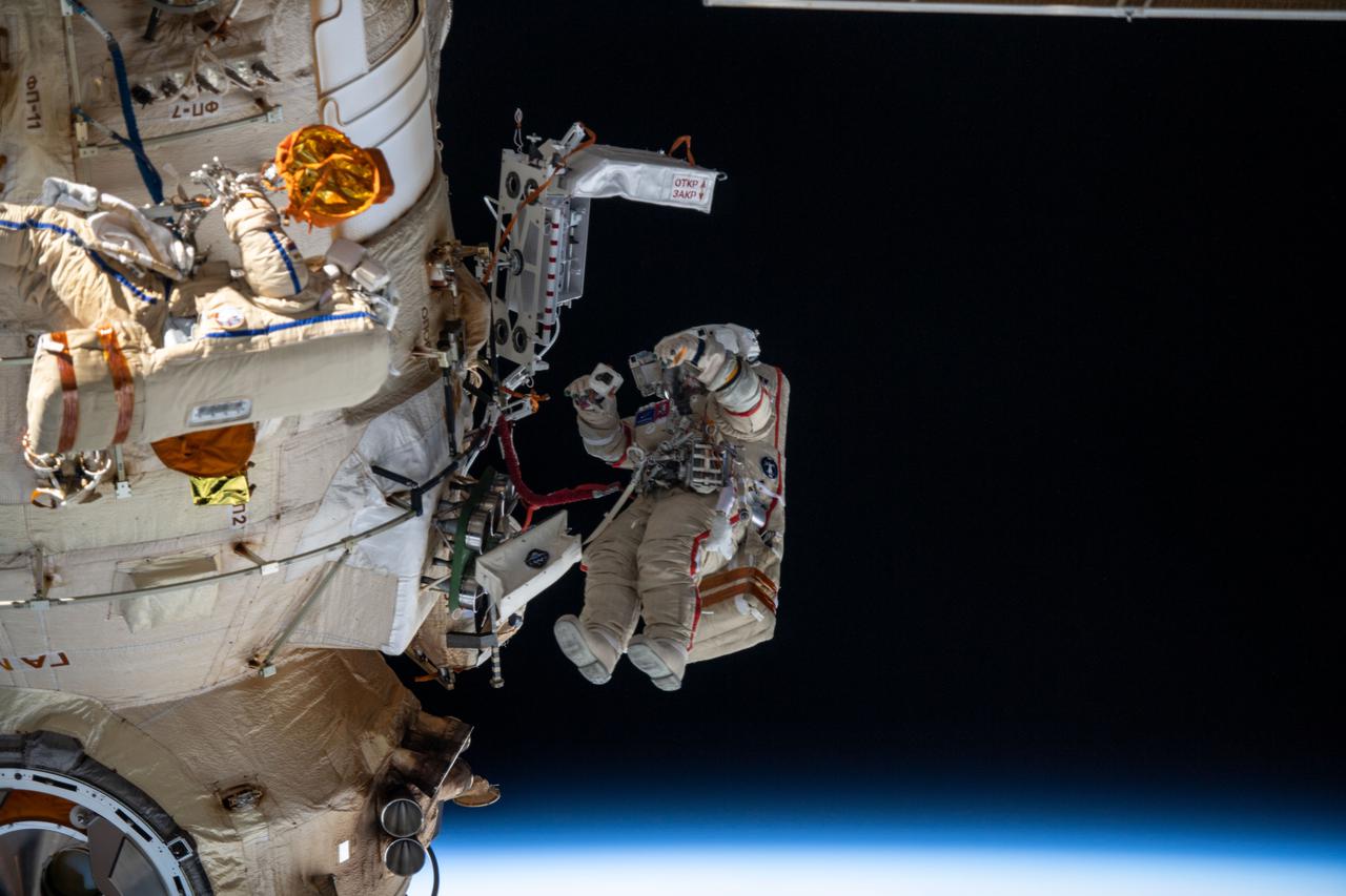 iss067e022065 (April 18, 2022) --- Two spacewalkers from Roscosmos are pictured working outside the Nauka multipurpose laboratory module as the International Space Station orbited 261 miles above the Gulf of St. Lawrence off the coast of Îsles de la Madeleine. Cosmonauts (from left) Denis Matveev and Oleg Artemyev worked outside the station's Russian segment for six hours and 37 minutes outfitting Nauka and configuring the European robotic arm.