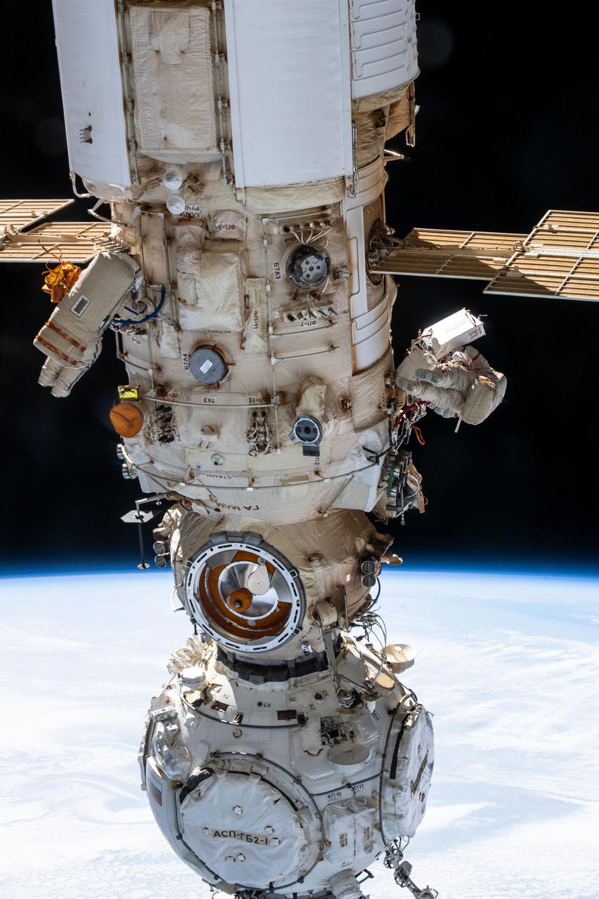 iss067e022083 (April 18, 2022) --- Two spacewalkers from Roscosmos are pictured on either side of the Nauka multipurpose laboratory module as the International Space Station orbited 260 miles above the Atlantic Ocean off the coast of Conakry, the capitol of Guinea. Cosmonauts (from left) Denis Matveev and Oleg Artemyev worked outside the station's Russian segment for six hours and 37 minutes outfitting Nauka and configuring the European robotic arm.
