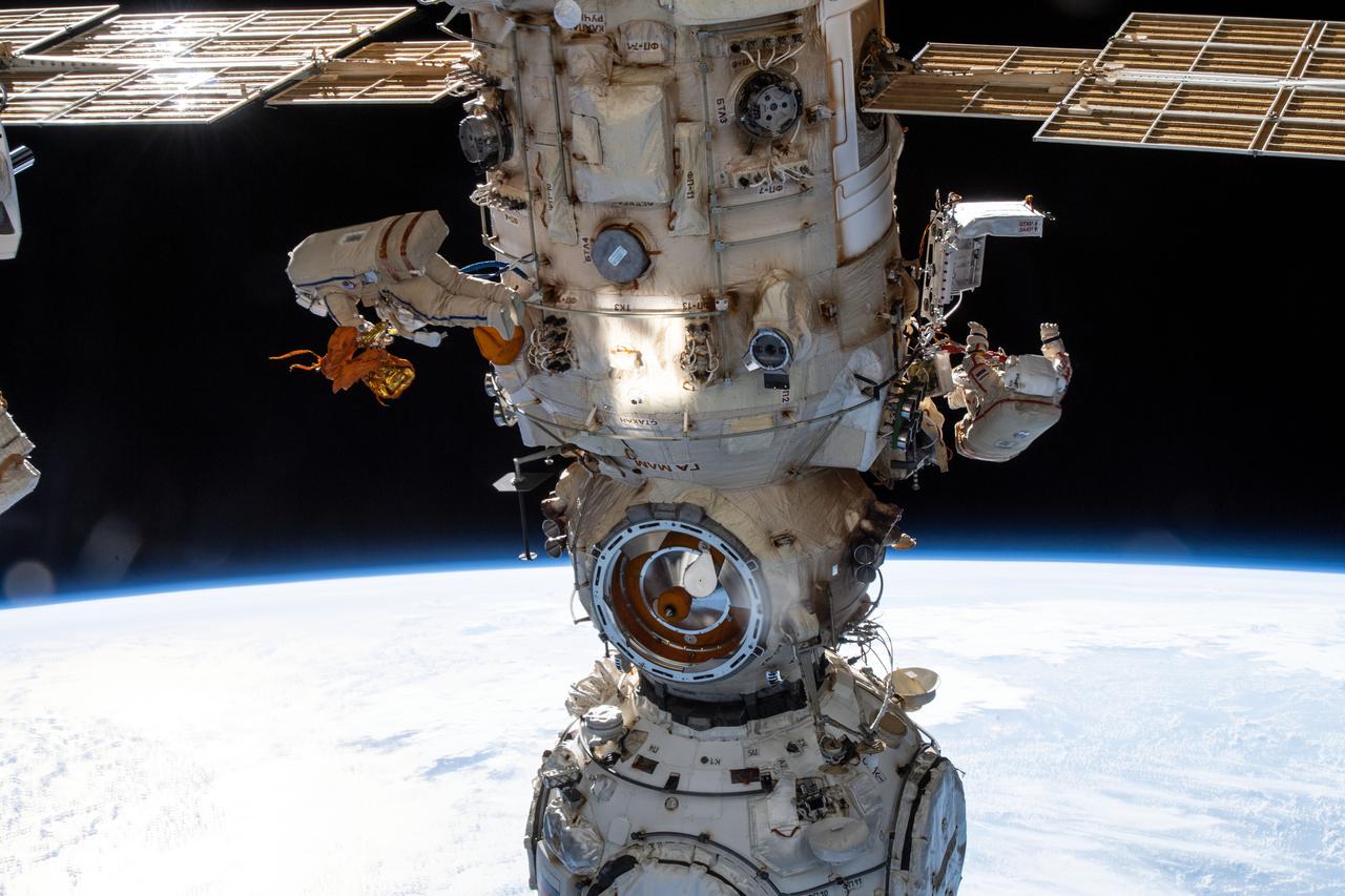 iss067e022091 (April 18, 2022) --- Two spacewalkers from Roscosmos are pictured on either side of the Nauka multipurpose laboratory module as the Intermtional Space Station orbited 263 miles above the Atlantic Ocean off the coast of Angola. Cosmonauts (from left) Denis Matveev and Oleg Artemyev worked outside the station's Russian segment for six hours and 37 minutes outfitting Nauka and configuring the European robotic arm.