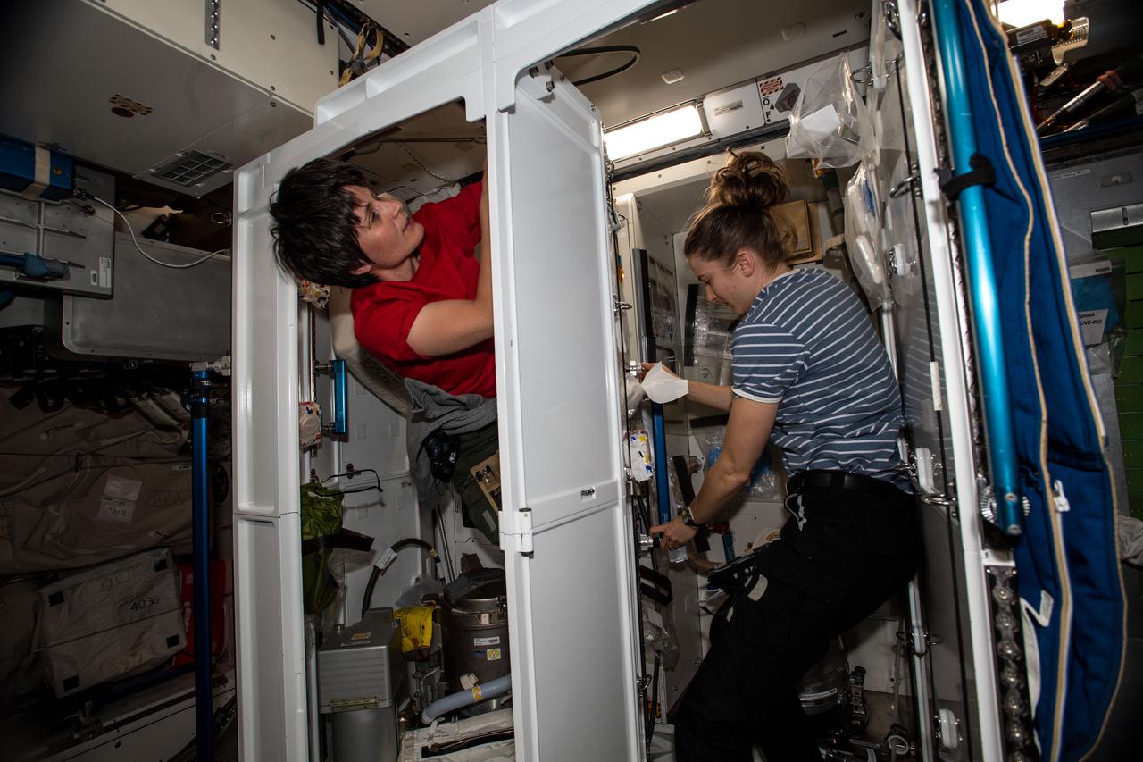 iss067e032402 (April 29, 2022) --- Expedition 67 Flight Engineers (from left) Samantha Cristoforetti of ESA (European Space Agency) and Kayla Barron of NASA partner together on orbital plumbing duties inside the two bathrooms aboard the International Space Station's Tranquility module.