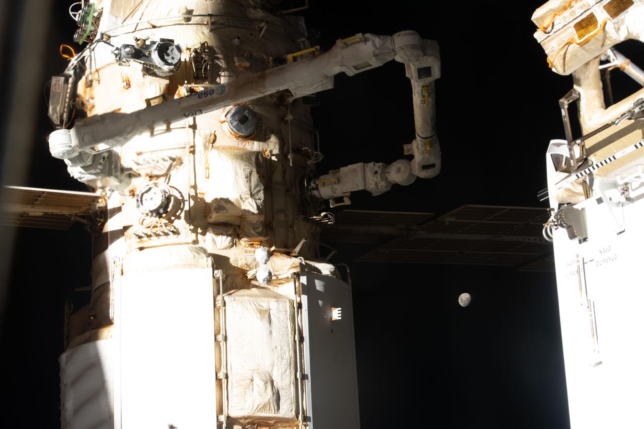 iss067e043927 (May 16, 2022) --- The Moon, with Earth's shadow draping across it during a lunar eclipse, is pictured in between the International Space Station's Nauka multipurpose laboratory module and the Rassvet module. Attached to Nauka, is the new European robotic arm that is continuing checkouts and mobility tests.