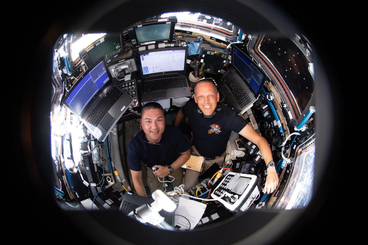 iss067e065648 (May 20, 2022) --- NASA astronauts (from left) Kjell Lindgren and Bob Hines are pictured inside the International Space Station's seven-windowed cupola monitoring the approach and rendezvous of Boeing's CST-100 Starliner spacecraft on the company's Orbital Flight Test-2 mission.