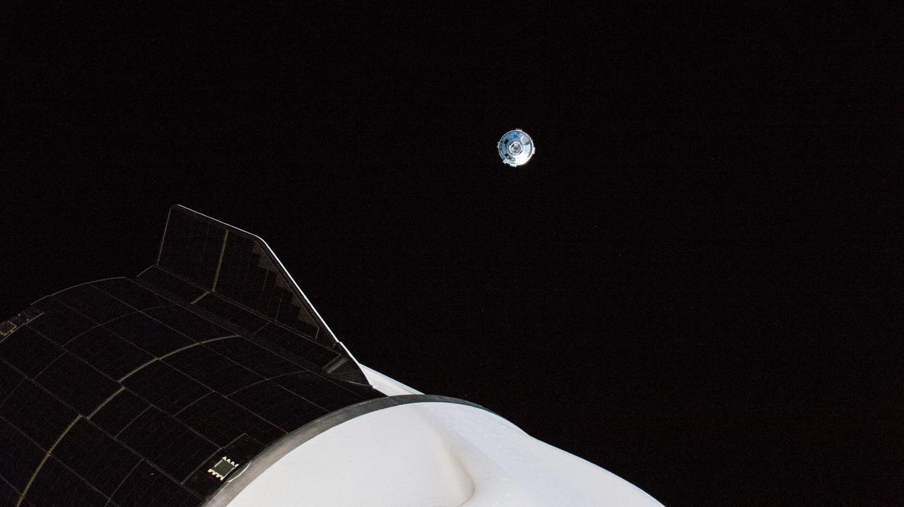 iss067e075991 (May 25, 2022) --- Boeing's CST-100 Starliner crew ship is pictured maneuvering away from the International Space Station after undocking from the Harmony module's forward port. In the foreground, is the aft end of the SpaceX Dragon Freedom crew ship that delivered the Crew-4 astronauts to the orbiting lab.