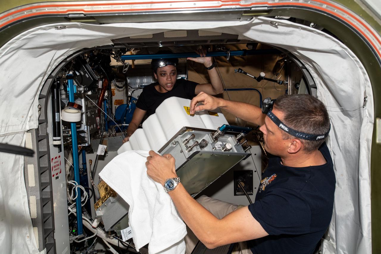 iss067e099398 (June 1, 2022) --- NASA astronauts and Expedition 67 Flight Engineers Bob Hines and Jessica Watkins perform maintenance inside the Tranquility module's Waste and Recycling System abaord the International Space Station.