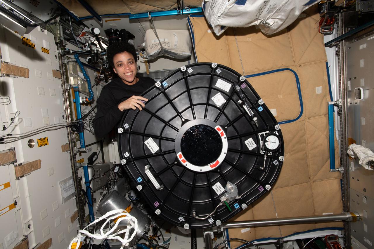 iss067e124513 (June 10, 2022) --- Expedition 67 Flight Engineer and NASA astronaut Jessica Watkins poses with the hatch cover belonging to the Bigelow Expandable Activity Module (BEAM) attached to the International Space tation's Tranquility module.