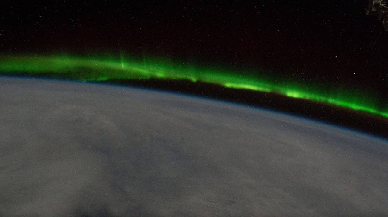 iss067e133437 (June 15, 2022) --- An aurora streams above a cloudy Earth as the International Space Station orbited 268 miles above the south Pacific.