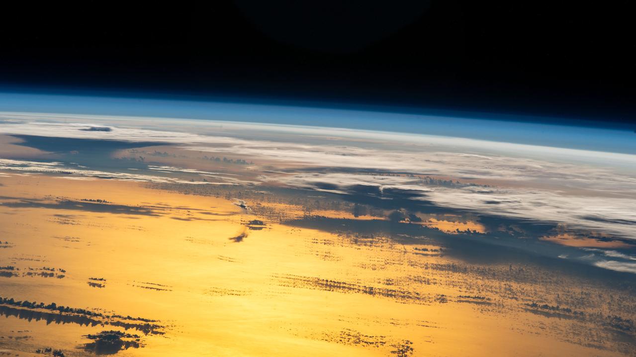 iss067e238146 (Aug. 4, 2022) --- The sun's glint beams off the Atlantic Ocean just before it sets creating a yellow-orange hue in this photograph from the International Space Station as it orbited 258 miles above.
