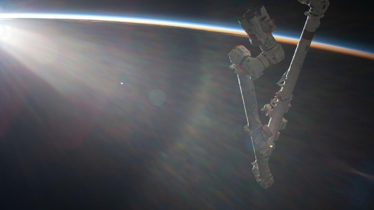 iss067e270598 (Aug. 18, 2022) --- An orbital sunrise begins illuminating Earth's atmosphere with the International Space Station's Canadarm2 robotic arm extending from the orbital lab as it soared 260 miles above the Pacific Ocean.