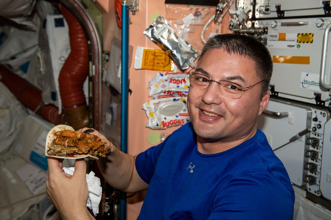 iss067e341284 (Aug. 16, 2022) --- NASA astronaut and Expedition 67 Flight Engineer Kjell Lindgren prepares to enjoy a taco during dinner time aboard the International Space Station.