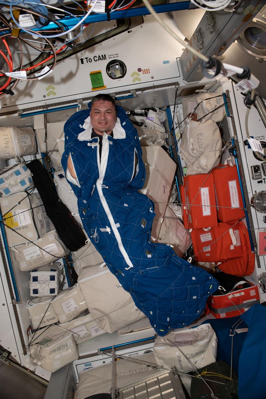 iss067e379057 (Sept. 23, 2022) --- NASA astronaut and Expedition 67 Flight Engineer Kjell Lindgren poses for a portrait inside a crew sleeping bag aboard the International Space Station.