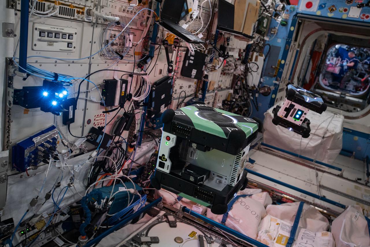 Documentation of two free-flying Astrobee robots (Queen and Bumble), equipped with LED Targets for the Smartphone Video Guidance Sensor (SVGS) experiment, during SVGS science 3 session. An SVGS LED Target is attached to the Life Sciences Glovebox (LSG) rack, JPM1F5 in the Kibo Japanese Experiment Module (JEM).