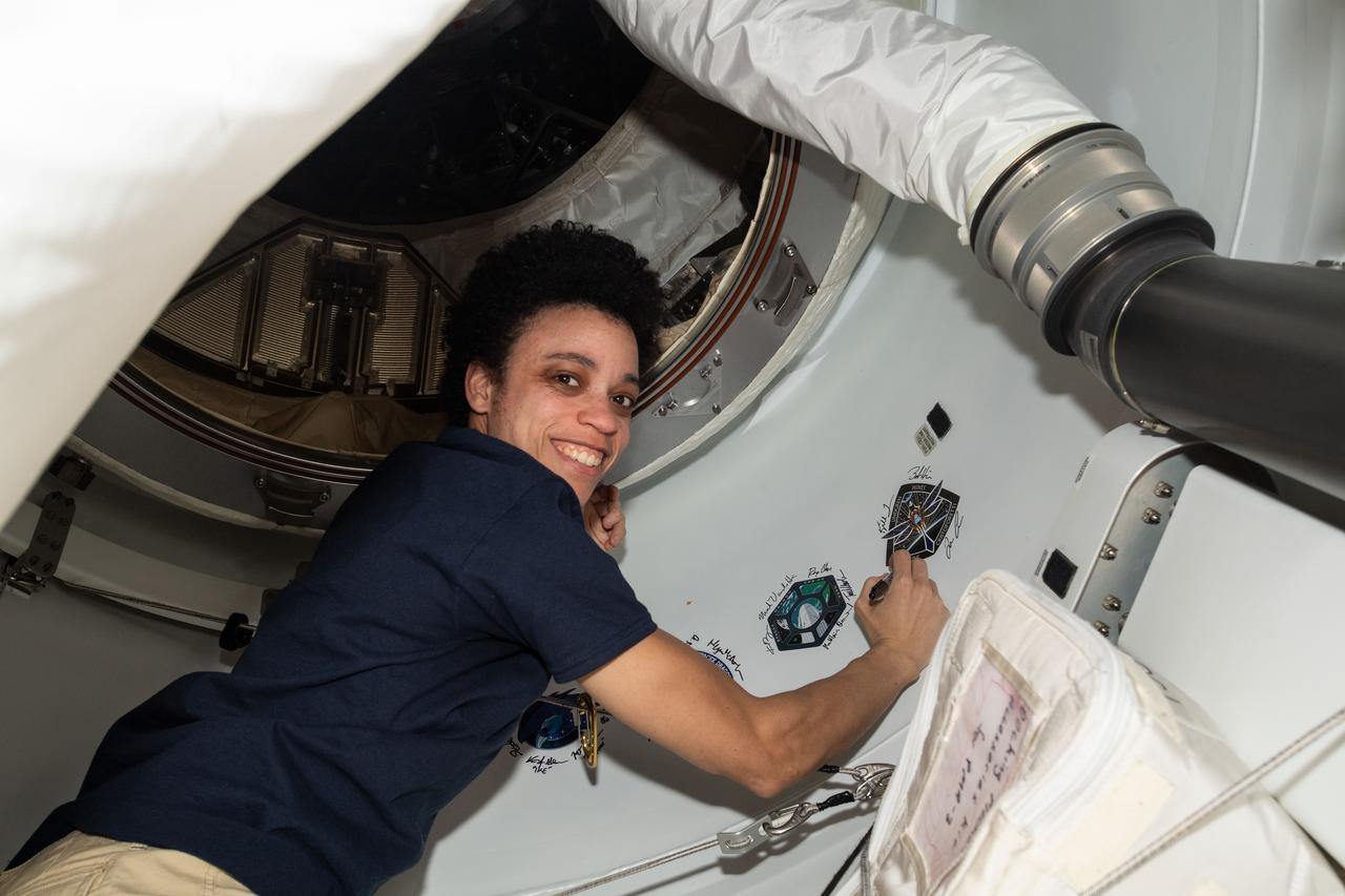 iss068e016462 (Oct. 12, 2022) --- NASA astronaut and Expedition 68 Flight Engineer Jessica Watkins, also a SpaceX Crew-4 Mission Specialist, signs her name around the Crew-4 mission insignia affixed to the vestibule between the Harmony module's space-facing port and the Dragon Freedom crew ship.