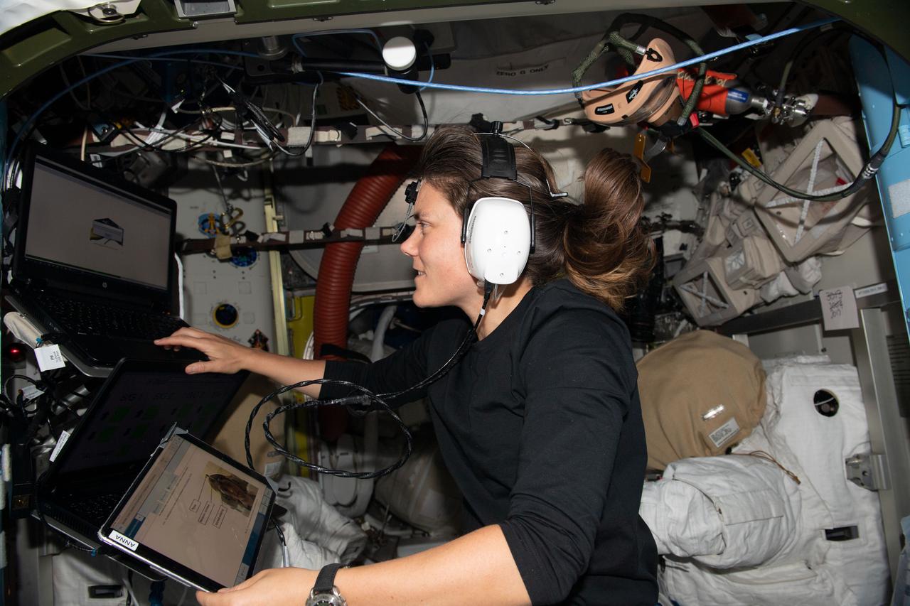 iss068e017876 (Oct. 21, 2022) --- Roscosmos cosmonaut and Expedition 68 Flight Engineer Anna Kikina is pictured wearing headphones for a hearing assessment taking place inside the Quest airlock. In the background at right, is a spacesuit stowed inside Quest where spacewalks are staged in the International Space Station's U.S. segment.