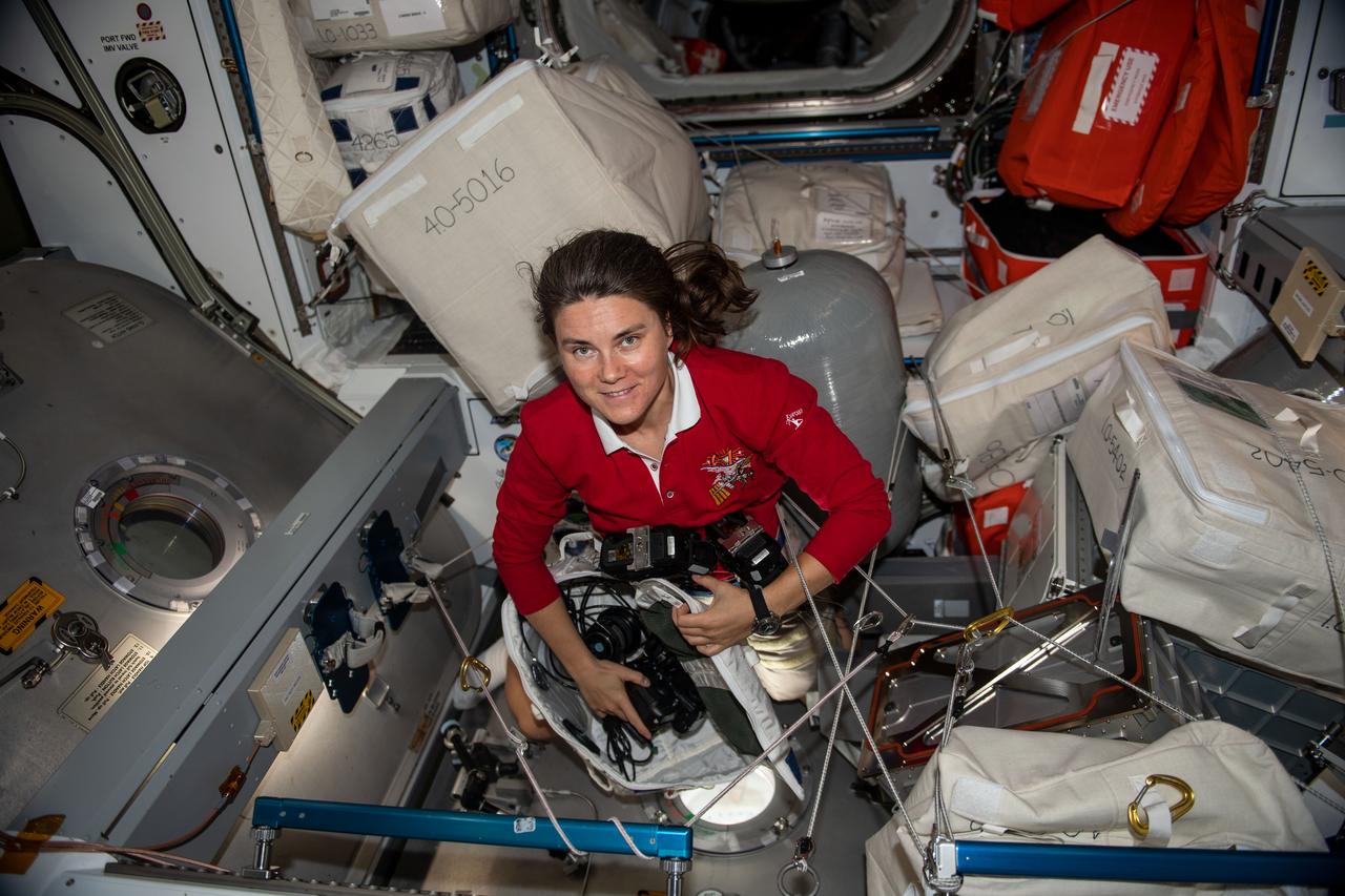 iss068e021032 (Nov. 7, 2022) --- Roscosmos cosmonaut and Expedition 68 Flight Engineer Anna Kikina prepares camera equipment for an Earth photography session through a hatch window on the International Space Station's Harmony module.
