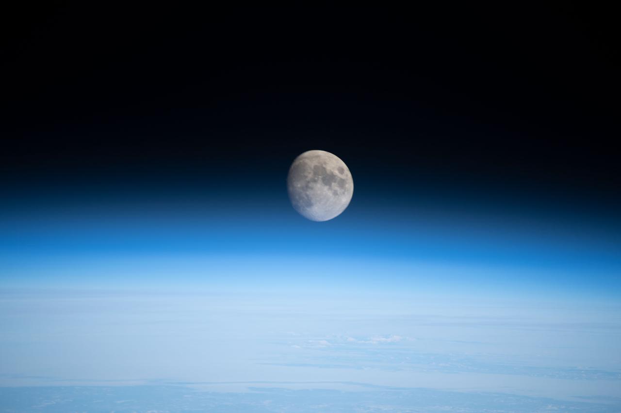 iss068e026672 (Dec. 4, 2022) --- The waxing gibbous Moon is pictured above Earth's horizon from the International Space Station as it orbited 261 miles over the northern Pacific Ocean. At the time of this photograph the Orion vehicle on the Artemis I mission was almost 24,000 miles away from the Moon and approximately 222,200 miles from Earth traveling at a speed of 3,076 miles per hour.