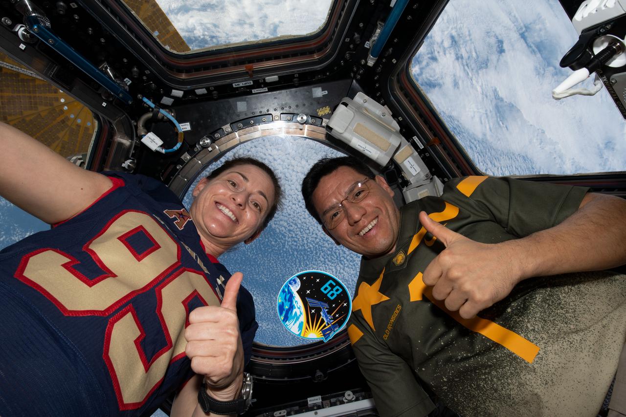 iss068e029132 (Dec. 10, 2022) --- Expedition 68 Flight Engineers Nicole Mann and Frank Rubio, both from NASA, pose with their mission's insignia inside the cupola as the International Space Station orbited 262 miles above the northern Pacific Ocean.