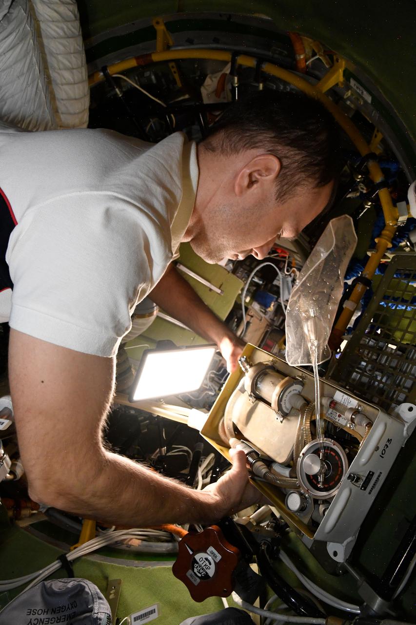 iss068e029377 (Dec. 12, 2022) --- Roscosmos cosmonaut and Expedition 68 Flight Engineer Dmitri Petelin services Orlan spacesuit life support components inside the International Space Station's Poisk module.