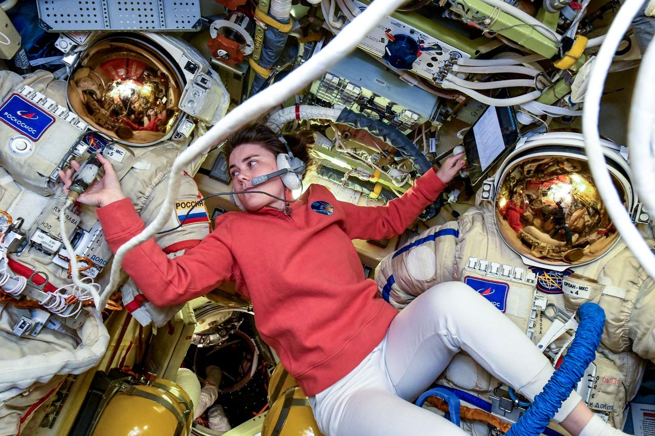 iss068e074720 (March 7, 2021) --- Roscosmos cosmonaut and Expedition 68 Flight Engineer Anna Kikina takes pressure measurements on a pair of Russian Orlan spacesuits inside the International Space Station's Poisk module.