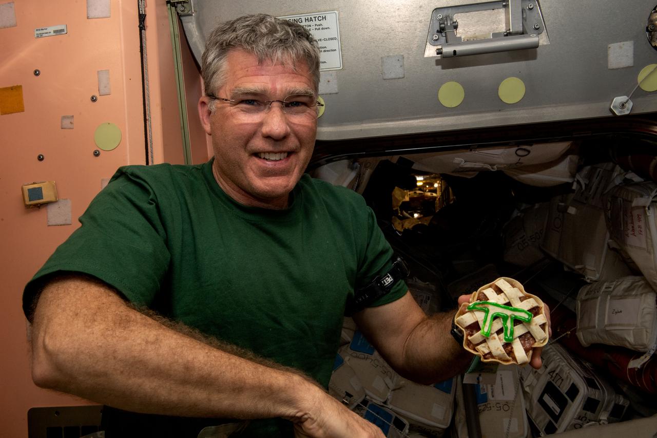 iss068e075336 (March 13, 2021) --- NASA astronaut and Expedition 68 Flight Engineer Stephen Bowen is pictured with a small pie in commemoration of Pi Day aboard the International Space Station.