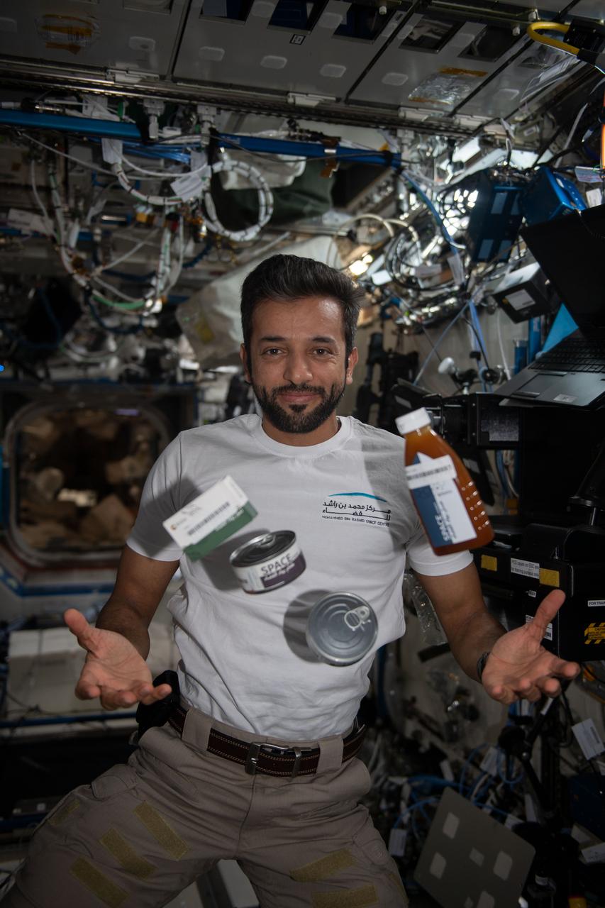 iss069e000263 (March 31, 2023) --- UAE (United Arab Emirates) astronaut and Expedition 69 Flight Engineer Sultan Alneyadi seemingly juggles food canisters and packages from the UAE in the microgravity environment of the International Space Station.