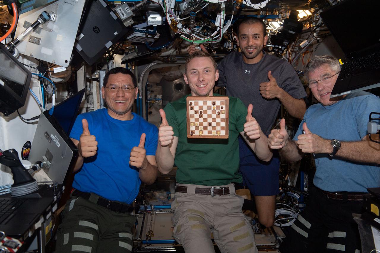 iss069e003898 (April 17, 2023) --- (From left) Expedition 69 Flight Engineers Frank Rubio, Woody Hoburg (both from NASA), Sultan Alneyadi from UAE (United Arab Emirates), and Stephen Bowen from NASA give a "thumbs up" after winning the first round of a space-to-ground chess tournament with mission controllers at NASA's Johnson Space Center in Houston, Texas. Hoburg is a chess fan and set up a chess tournament with mission controllers with each side having their own chess board and typically making one or two moves a day during their busy schedules.