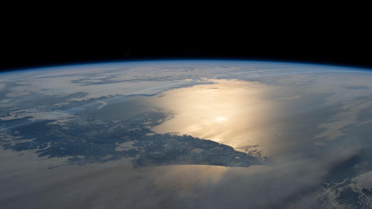 iss069e005463 (April 26, 2023) --- The Sun's glint breams across the Pacific Ocean and the Sea of Okhotsk, with the southern portion of the Kamchatka Peninsula in between, in this photograph from the International Space Station as it orbited 264 miles above.