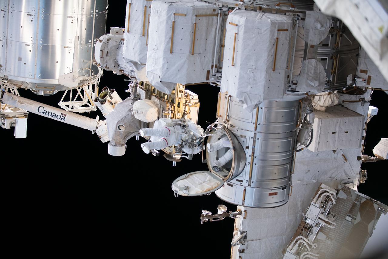 iss069e008015 (April 28, 2023) --- NASA astronaut Stephen Bowen and UAE (United Arab Emirates) astronaut Sultan Alneyadi (partially obscured) are pictured in their Extravehicular Mobility Units, or spacesuits, exiting the International Space Station's Quest airlock and beginning a spacewalk. The duo would spend seven hours and one minute in the vacuum of space routing cables and installing insulation readying the orbital outpost for its next set of roll-out solar arrays due to be installed after their delivery on the next SpaceX Dragon cargo mission.